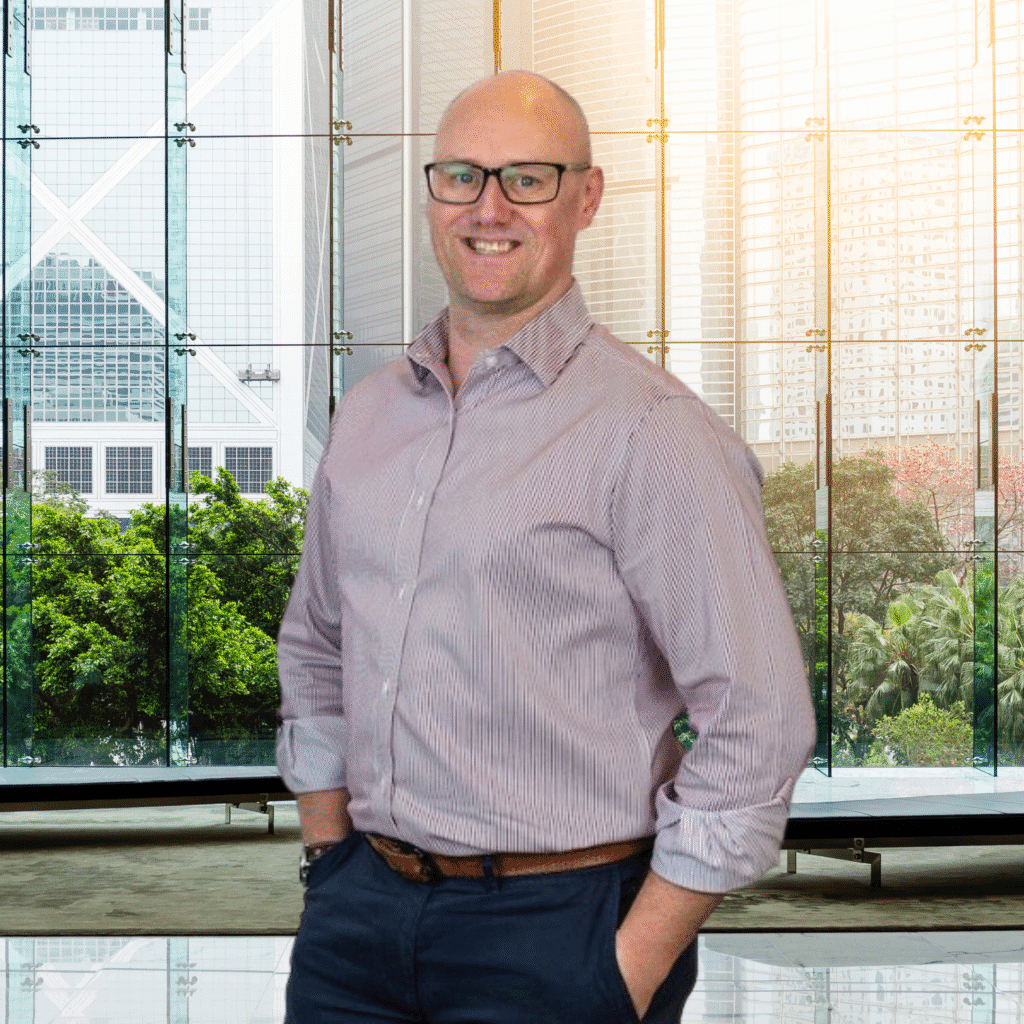 Smiling man with glasses, wearing a striped shirt. Modern office building background. Home page image.