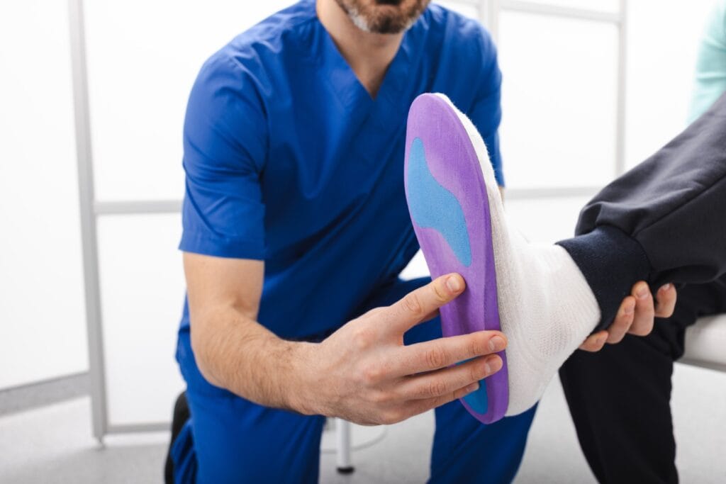 Orthopedist fitting custom orthopedic insole to patient's foot. Foot care, podiatry, and healthy feet concept.